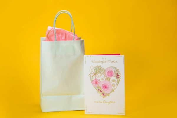 A beautifully designed Mother's Day card and gift bag on a vibrant yellow background, perfect for celebrating a special occasion.